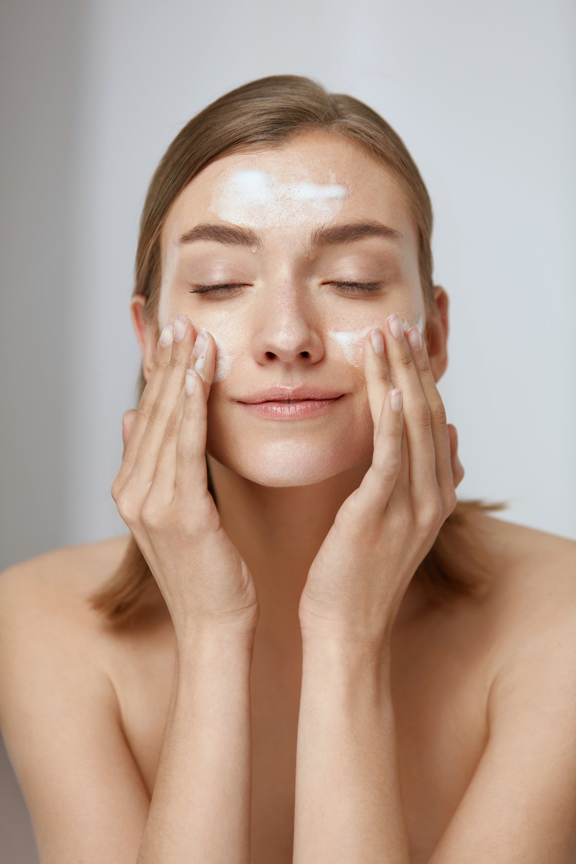 Face skin care. Woman cleaning facial skin with foam soap